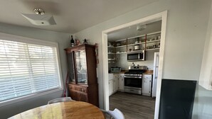 A kitchen with a wooden dining table, white cabinets, a microwave, stove, and a refrigerator. - Cozy cottage in delightful Ahwahnee with AC, WiFi (Ahwahnee)