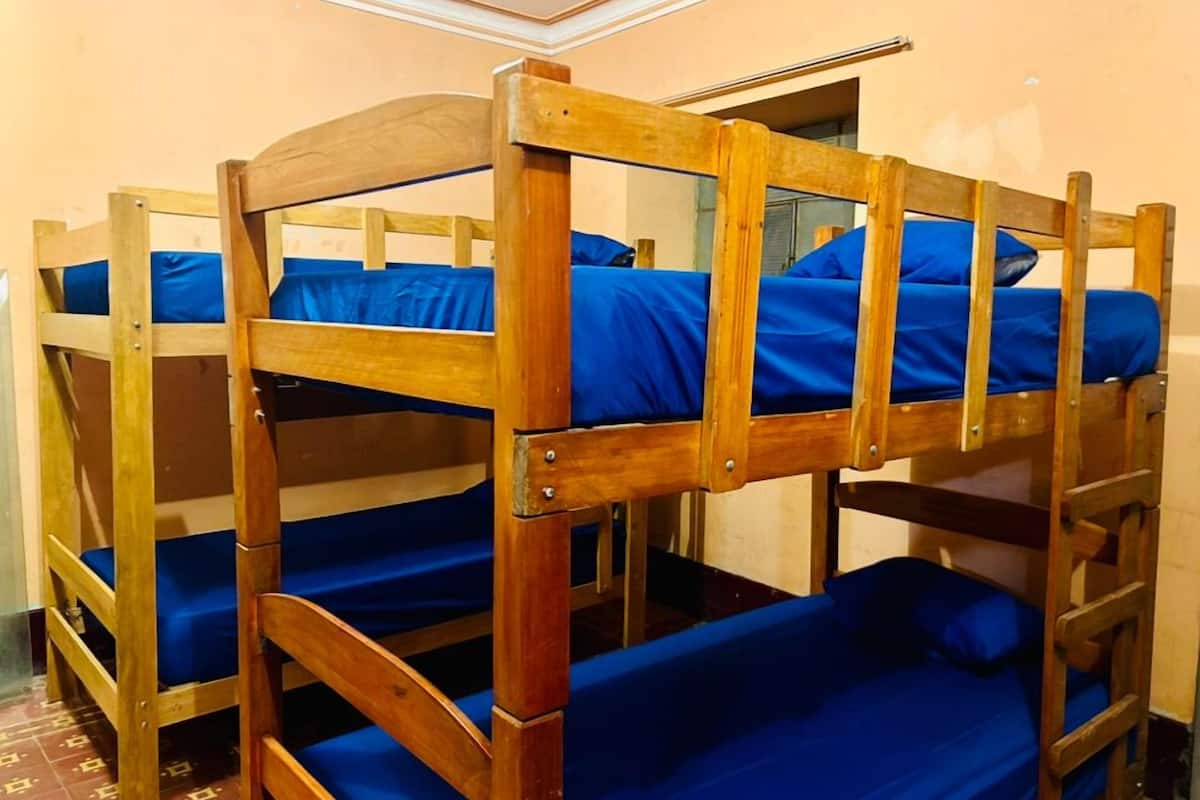 Ein Stockbett mit blauer Bettwäsche in einem Zimmer mit schlichten Wänden und einem Fliesenboden.