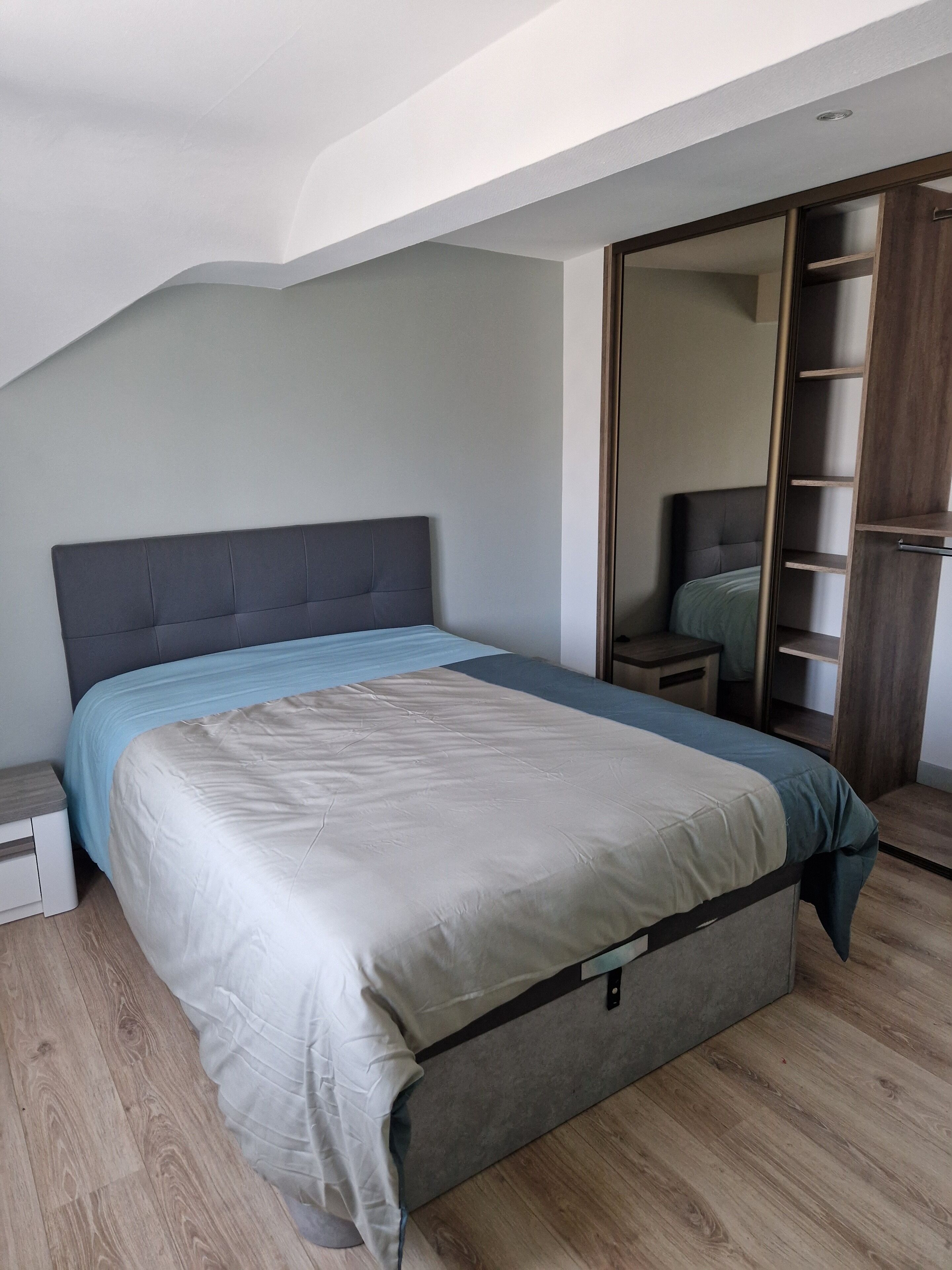 Une chambre à coucher avec un lit, une table de chevet, une armoire et un plancher en bois.