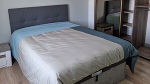 A bedroom with a bed, a nightstand, a wardrobe, and a wooden floor. - Appartement Sous Combe Climatisé 2 éme Étage (Publier)