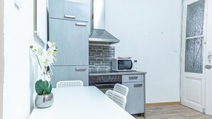 A compact kitchen with a microwave, stove, and grey cabinets. - Family-friendly 2BR Apt.-Perfect for Longstays (Vienna)