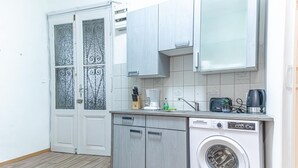 A compact kitchen with a washing machine, a coffee maker, and a knife block. - Family-friendly 2BR Apt.-Perfect for Longstays (Vienna)