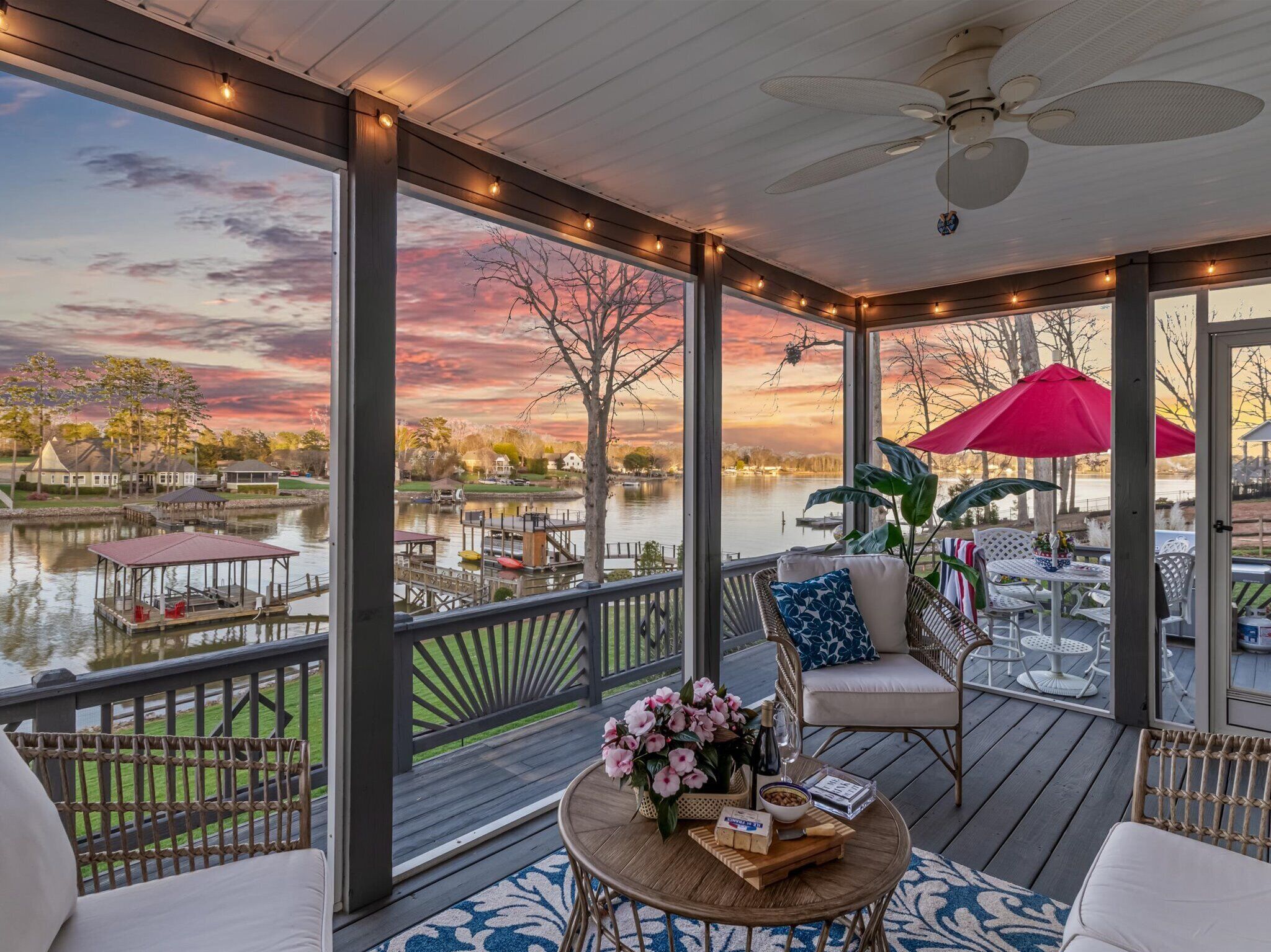 Screened porch with cozy seating and sunset lake views.
