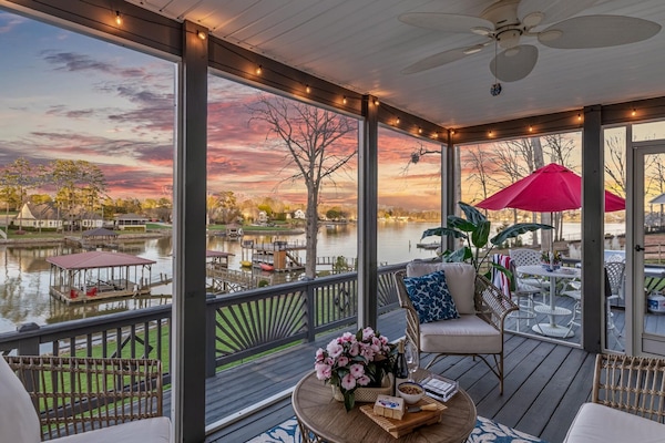 Screened porch with cozy seating and sunset lake views.