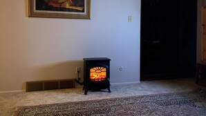 Una habitación con un estufa de leña, un cuadro en la pared y un tapete estampado en el suelo.