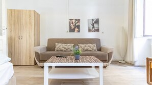 A living room with a sofa, coffee table, and a potted plant. - Chic Apartment Suitable for Longstays in Lockdown (Vienna)