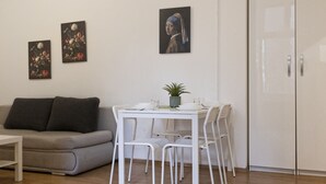Un soggiorno moderno con un divano, un tavolo da pranzo con sedie e due opere d'arte incorniciate al muro.