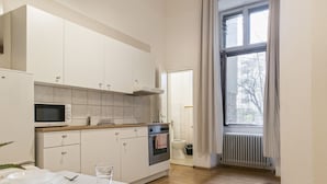 Una cucina moderna con mobili bianchi, un forno a microonde, un forno e una finestra con tende.