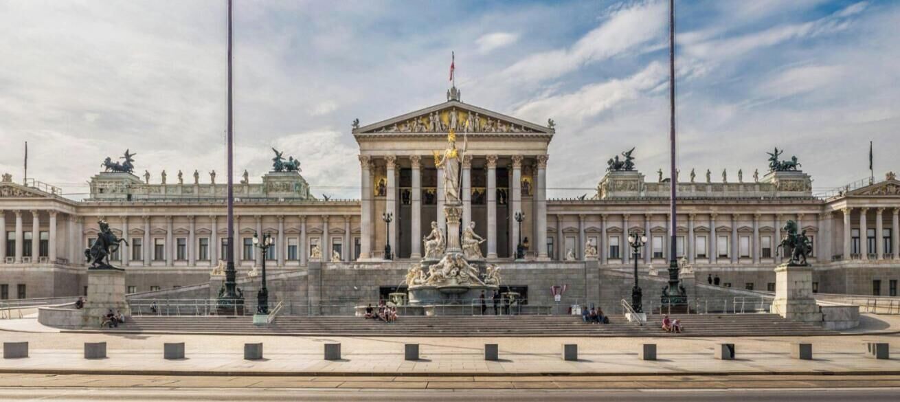 A grand building with a central fountain, symmetrical wings, and classical columns.