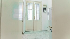 A hallway with a double door, a tiled floor, and a wall-mounted electrical box.