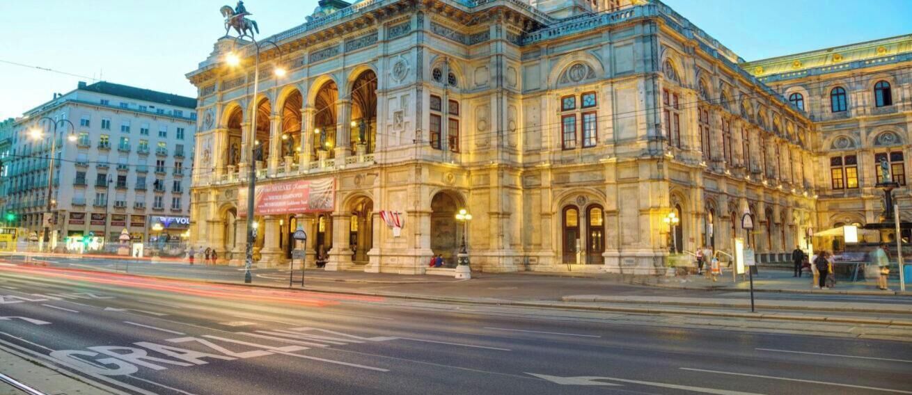 A historic building with classical architecture, a prominent entrance, and a statue on top.