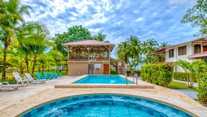 A pool area with a clear blue pool, lounge chairs, and a covered seating area. - Studio 1 for four to five guests (Parrita)