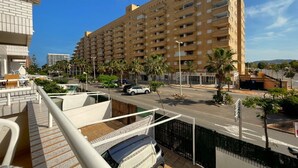 A high-rise hotel with multiple balconies, a parking area, and palm trees.