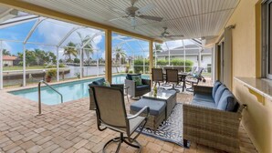 A covered outdoor area with a pool, seating, and a view of a body of water and palm trees. - 618 via Tunis (Punta Gorda)