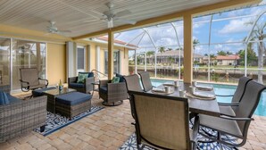 A covered outdoor area with wicker furniture, a pool, and a view of a residential area. - 618 via Tunis (Punta Gorda)