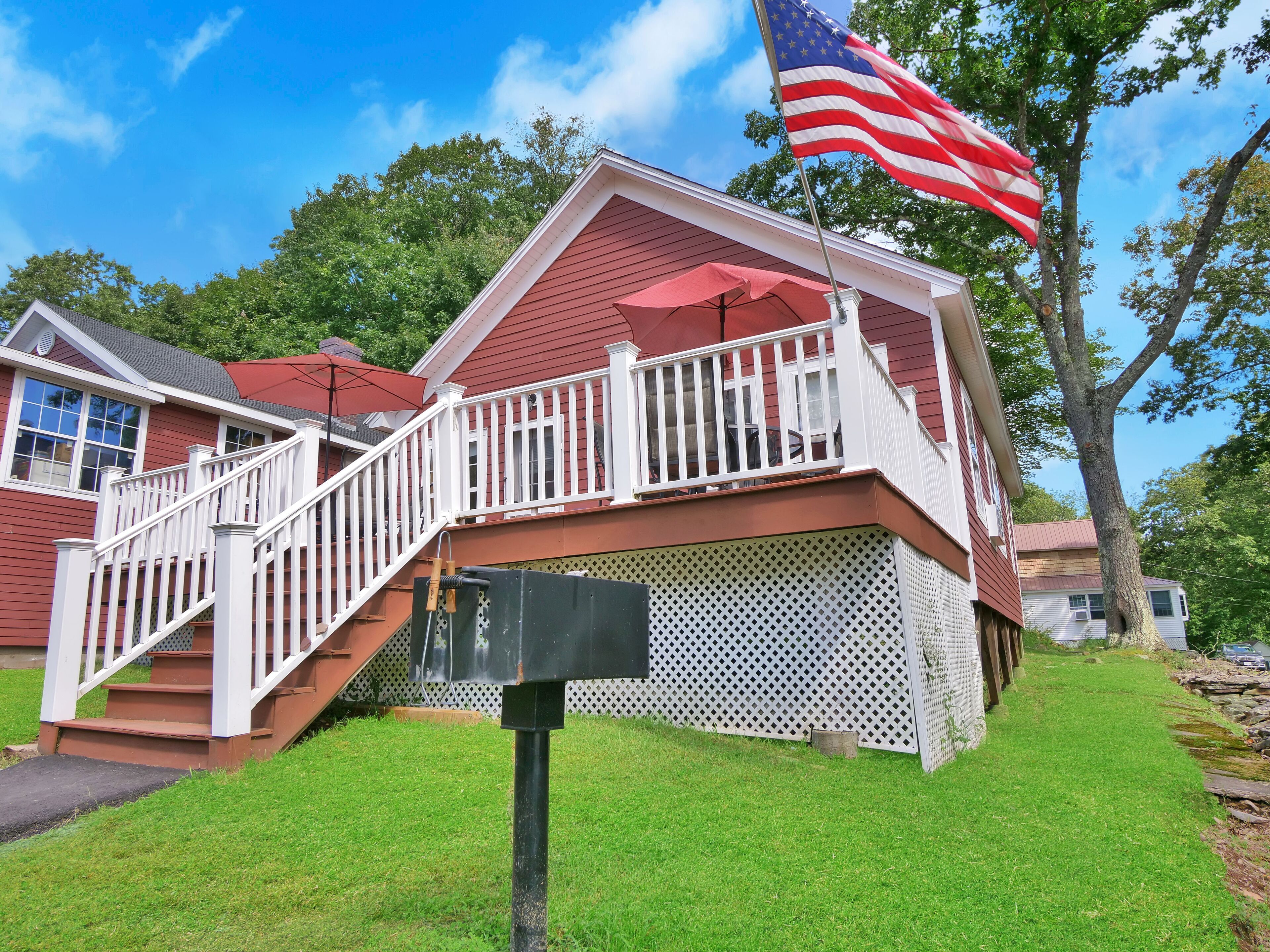 A two-story house with a red exterior, white railings, and a red roof.