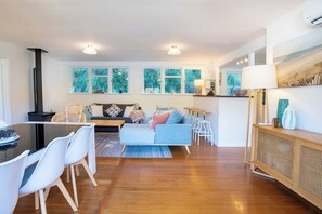 Una sala de estar moderna con un sofá, una mesa de comedor, sillas y una cocina con estufa.