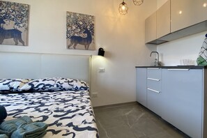 Une chambre à coucher comprenant un lit, une table de chevet, une commode et une lampe fixée au mur.