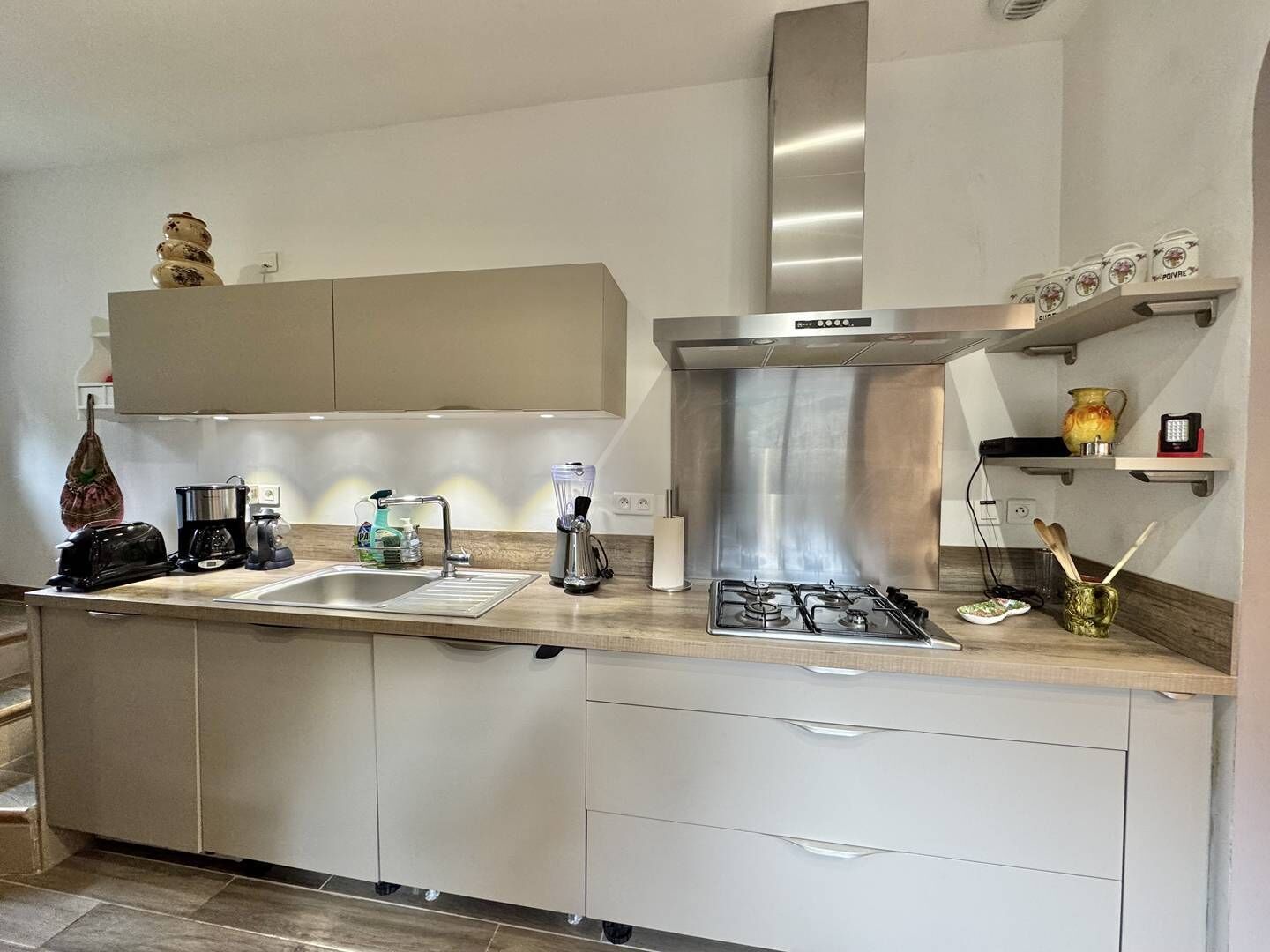 Een moderne keuken met een roestvrijstalen afzuigkap, een dubbele spoelbak en een inbouwoven.