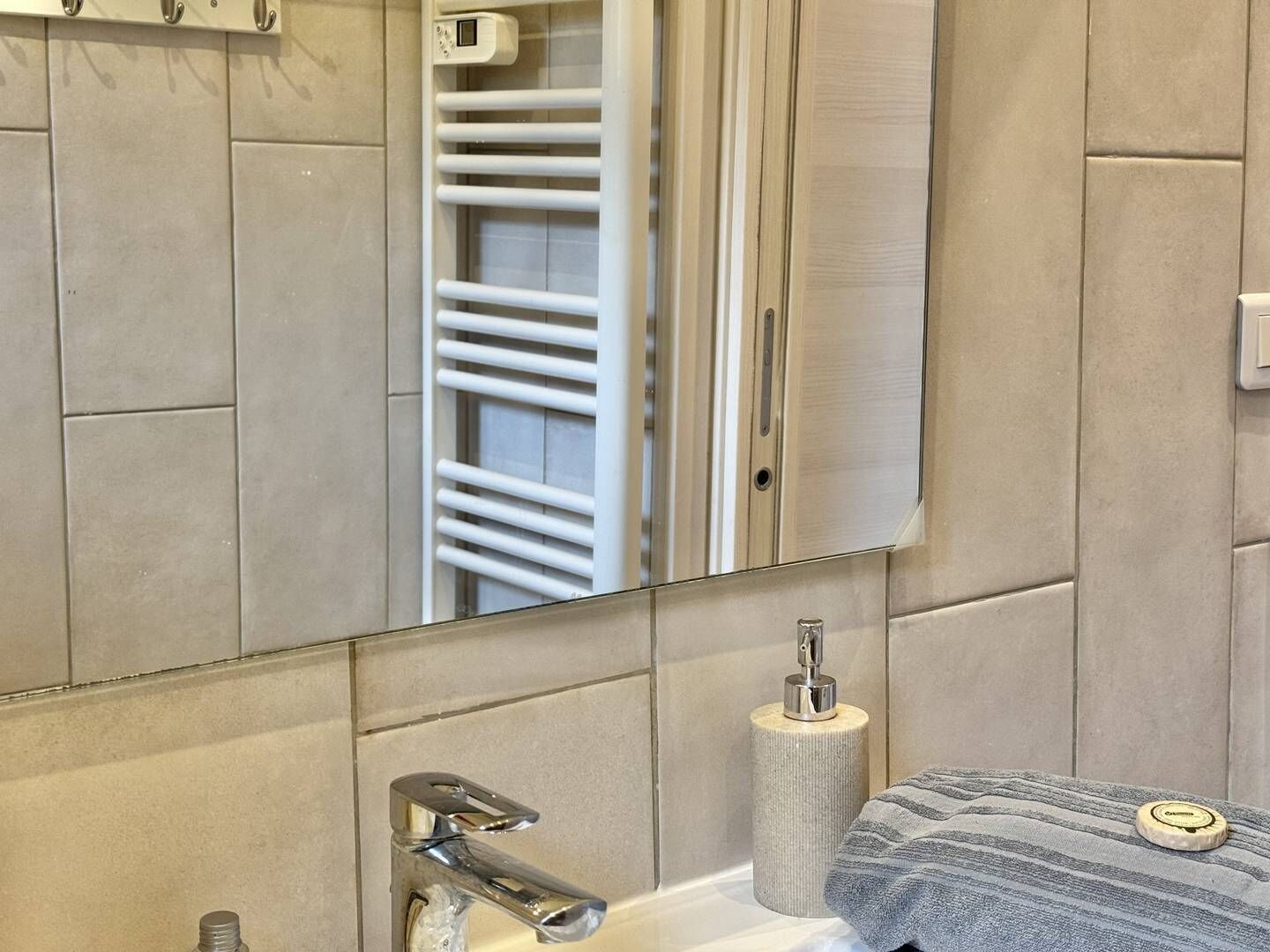 Un bagno con uno specchio, un porta asciugamani, un portasciugamani di carta e un lavandino.