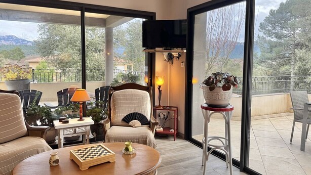 Una sala de estar moderna con un ventanal grande, una chimenea y un tablero de ajedrez sobre una mesa de centro.
