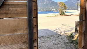 Une structure en bois offrant une vue sur une plage et, au loin, sur des montagnes.