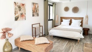 Une chambre à coucher avec un lit, un banc, un vase et des œuvres d’art mural.