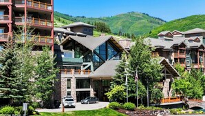 Un hotel de varios pisos con un diseño arquitectónico moderno, que cuenta con grandes ventanales y fachada de piedra.