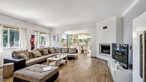A spacious living room with a large sectional sofa, a flat-screen TV, and a dining area with chairs and a table. - Quinta Valente VIP Properties by Interhome (Silves)