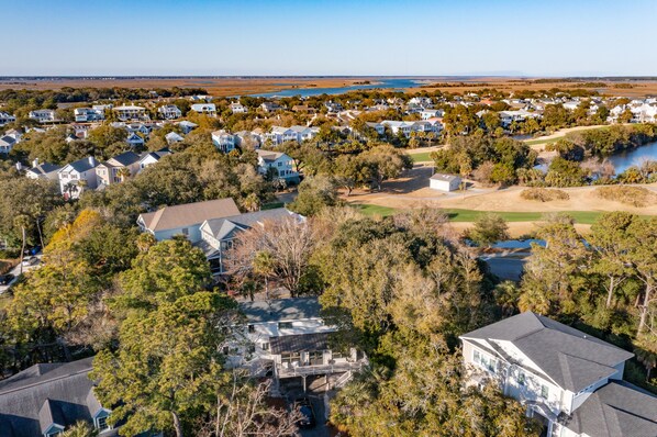A residential area with houses, trees, and a body of water in the background.