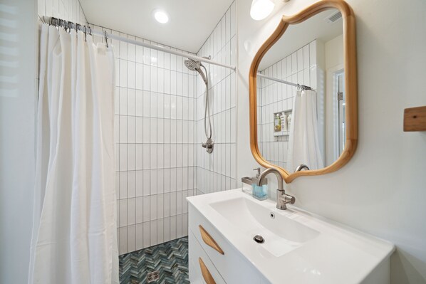Une salle de bain avec une douche, un lavabo et un miroir.