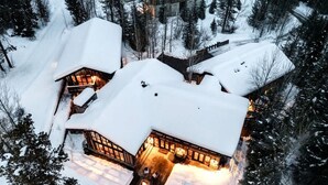 A snow-covered lodge with a central fireplace, surrounded by snow-covered trees. - Abode on the Big Trail, access to ski runs (Teton Village)
