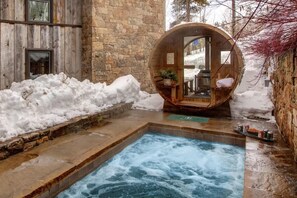 Un área de spa con un jacuzzi, paredes de piedra y una estructura de barril de madera.