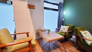 A room with a wooden table, two chairs, a small potted plant, and a window with curtains. - EZO Run Sapporo - Hostel (Sapporo)