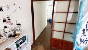 A traditional Japanese room with tatami flooring, a shoji screen door, and a small desk with a computer and decorative items. - EZO Run Sapporo - Hostel (Sapporo)