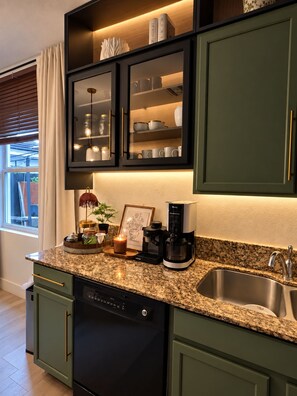 A kitchen with a dishwasher, coffee maker, and a window with blinds. - Villa Oasis at Florida. 4 Bed, 3bath 8 People (Homestead)