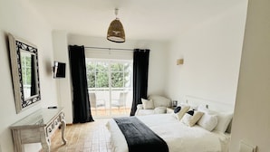 Une chambre à coucher avec un lit, une commode, un miroir et un téléviseur.