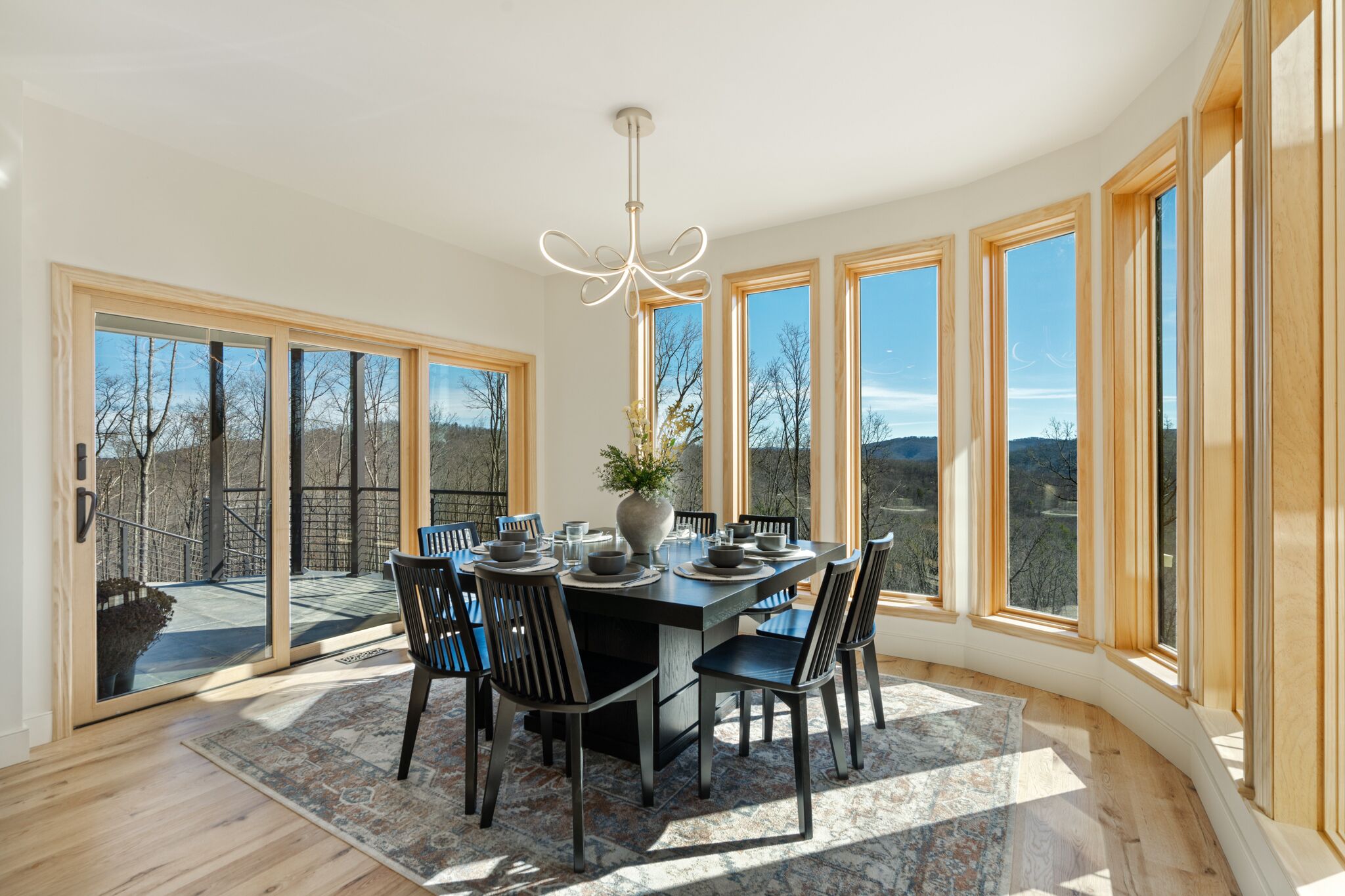 A dining area with a large table, chairs, and a chandelier.