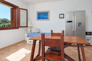 Un dormitori amb un llit, una finestra, un quadre, un refrigerador i una taula.