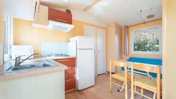 Een koelkast, een magnetron, een kookplaat, kookgerei, borden en bestek