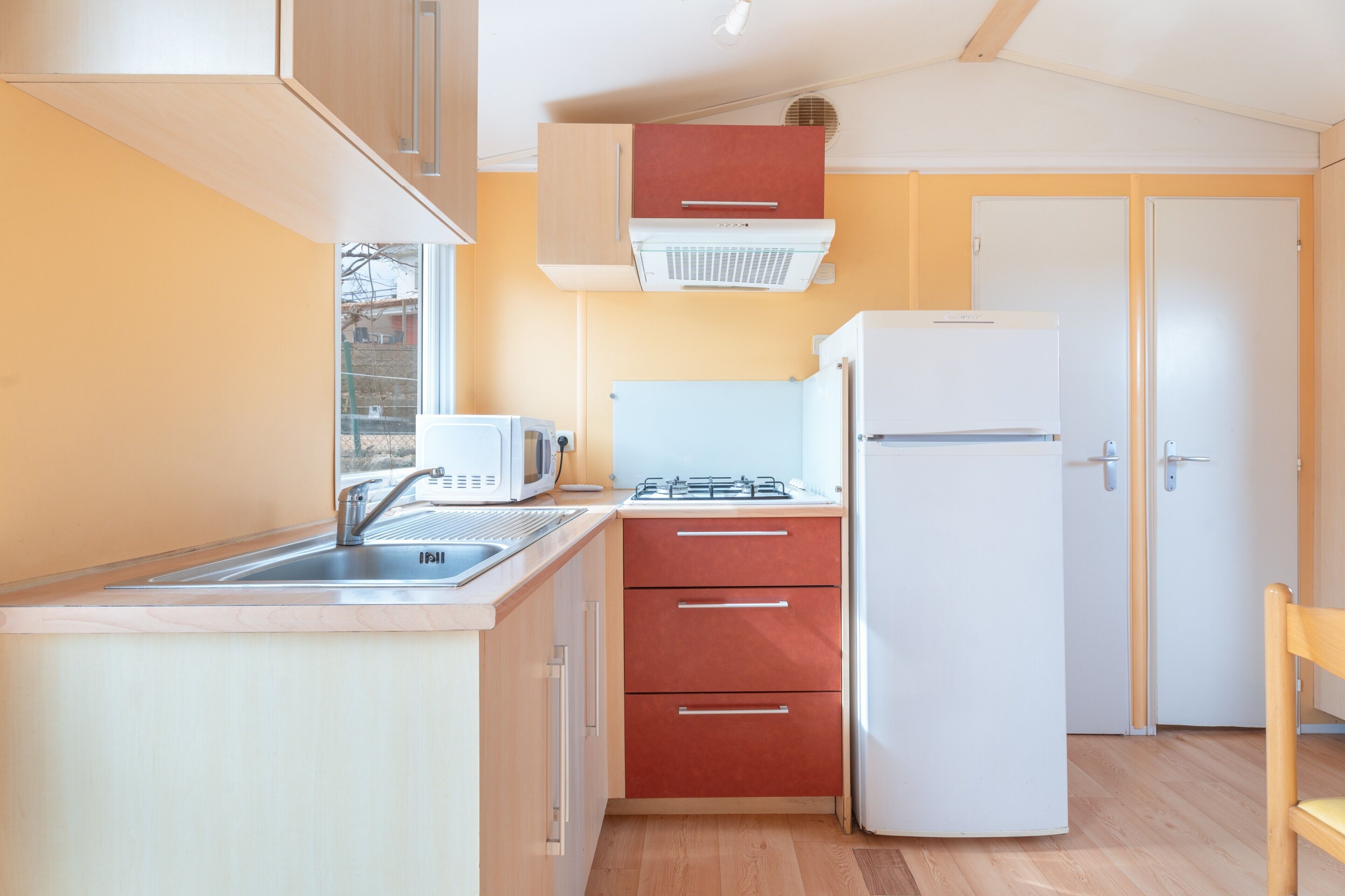 Een koelkast, een magnetron, een kookplaat, kookgerei, borden en bestek