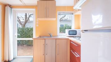 Een koelkast, een magnetron, een kookplaat, kookgerei, borden en bestek