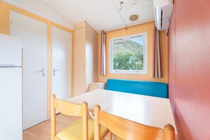 A compact room with a bed, a table, and a window with a view of greenery.