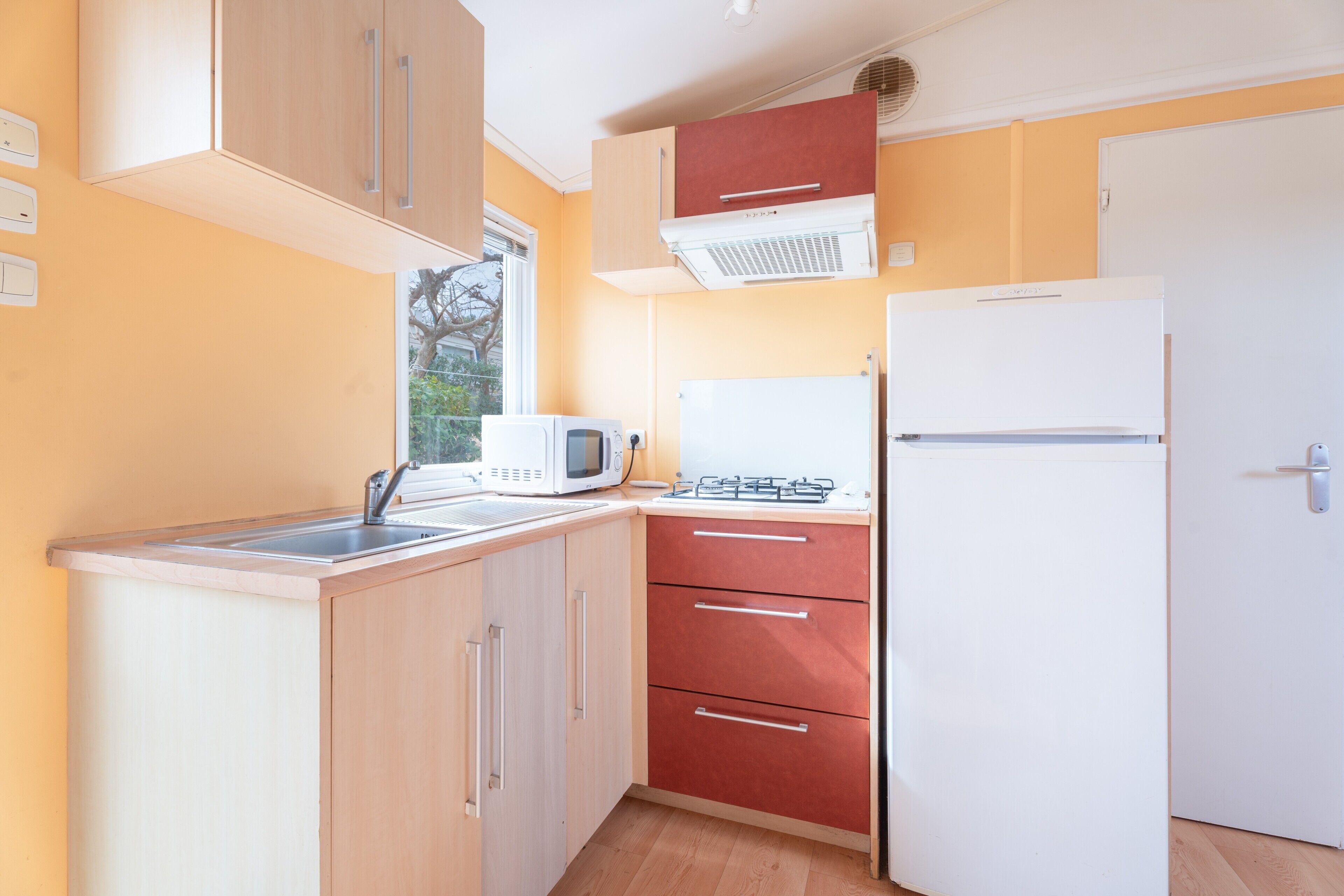 Una cucina compatta con forno a microonde, fornelli e frigorifero.