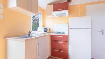 Una cucina compatta con forno a microonde, fornelli e frigorifero.