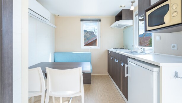 Une cuisine compacte avec un coin repas, un four à micro-ondes intégré et une fenêtre donnant sur un paysage agréable.