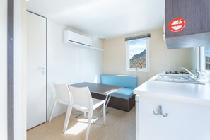 A compact kitchenette with a sink, a window with a mountain view, a blue bench, and a white chair. - Holiday Home 'BW 2018' with Mountain View, Wi-Fi and Air Conditioning (Bárig)