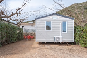 A small white mobile home with two windows, a door, and an air conditioning unit. - Holiday Home 'BW 2018' with Mountain View, Wi-Fi and Air Conditioning (Bárig)