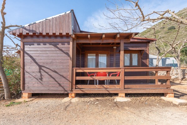 A wooden cabin with a balcony, a small table, and two chairs. - Holiday Home 'Cabaña Madera B' with Mountain View, Wi-Fi and Air Conditioning (Bárig)