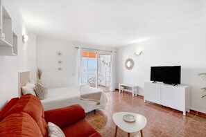 A modern room with a bed, a sofa, a TV, and a small table.